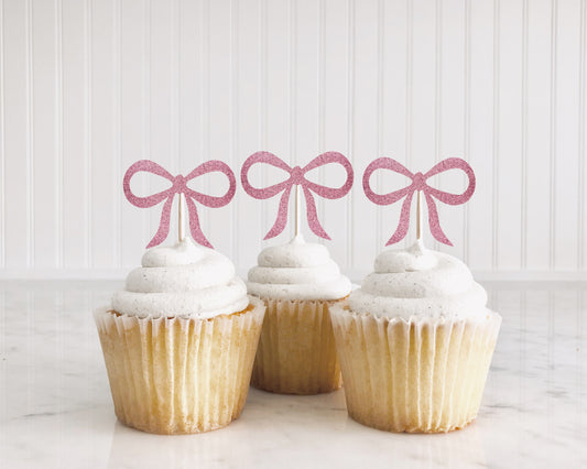 cupcakes with glitter pink bows on top of them