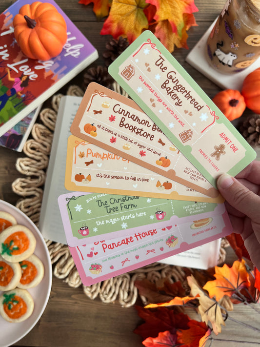 Set of colorful cards with dream harbor book series designs on a wooden table with fall leaves and cookies.