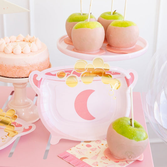 pink cauldron paper plates on a table with pink caramel apples
