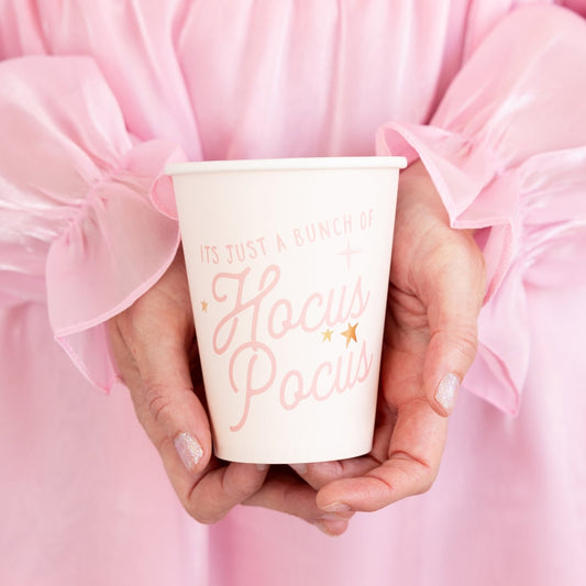 pink paper cups with it's just a bunch of hocus pocus written on the front of them and being held in someone's hands