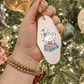 Keychain with a cartoon duck design held in front of a decorated Christmas tree.