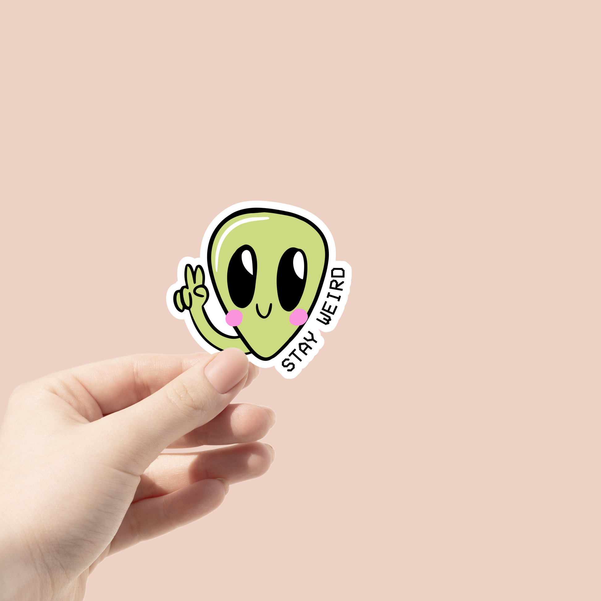 green alien making a peace sign that says "stay weird" sticker