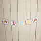 A birthday banner with the number 1, circus-themed pennants, and decorative elements, strung across a wall.